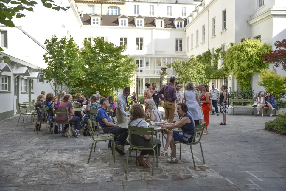 People sitting in green chairs on a patio in Paris