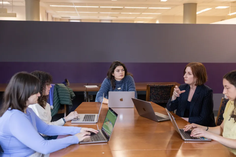 Prof. Caroline Melly and her students gather around a conference table to discuss their research