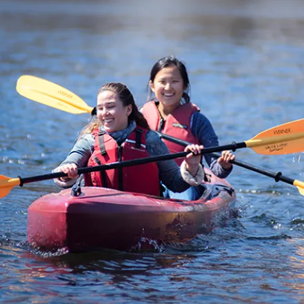 Two students paddling a canoe on the pond